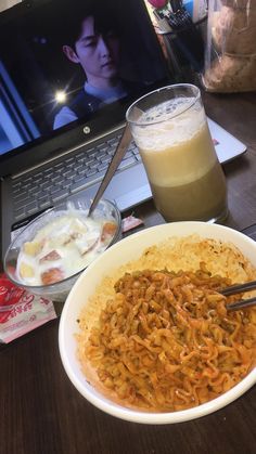 a bowl of food next to a laptop on a table