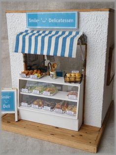 a small food stand with blue and white striped awnings on the top shelf