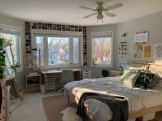 a bed room with a neatly made bed next to two windows and a ceiling fan