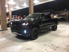 a black truck parked in front of a gas station