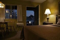 a bed room with a neatly made bed and a night stand next to a window