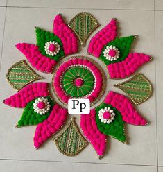 a pink flower with green leaves and white flowers in the center on a tile floor