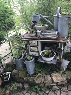 an old stove with pots and pans on top of it in a garden area