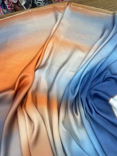 a close up view of a blue and orange silk material on a wooden table with other items in the background