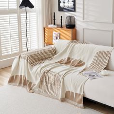 a white couch covered in a blanket next to a window