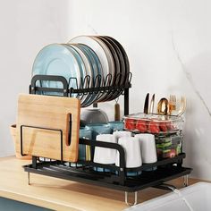 the dish rack is holding many plates and silverware, while another plate holder holds several glasses