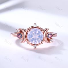 an oval shaped ring with pink and blue stones in the center on a white surface