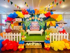 an outdoor party setup with balloons, streamers and decorations on the ground in front of a white picket fence