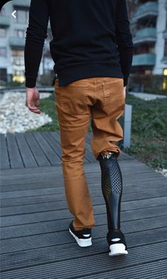 a man walking on a wooden walkway with an umbrella attached to his foot and wearing black shoes