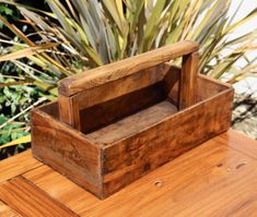 a wooden box sitting on top of a wooden table next to some grass and plants