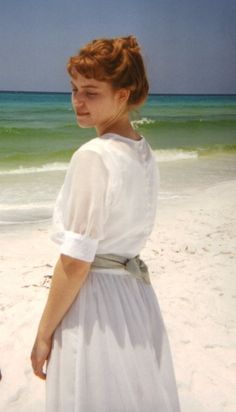 a woman standing on top of a beach next to the ocean