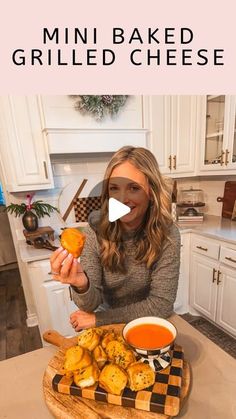 a woman holding up a piece of bread on top of a wooden cutting board