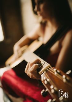 a woman is playing an acoustic guitar