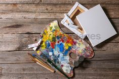 an artist's palette with paint and brushes on a wooden table next to it