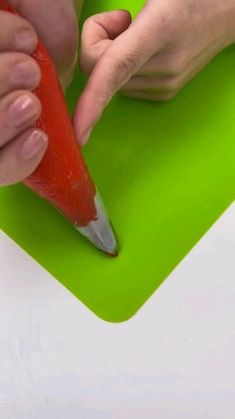 a person is holding a carrot on a cutting board