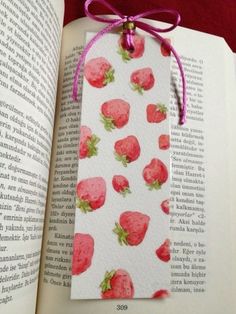 a bookmark with strawberries on it sitting in front of an open book,