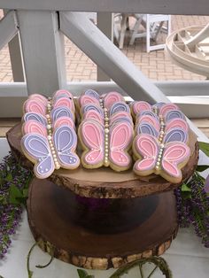 decorated cookies sitting on top of a wooden stand next to purple and white flowers in front of a window