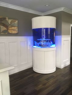 a fish tank sitting on top of a wooden floor next to a white cabinet with blue lights