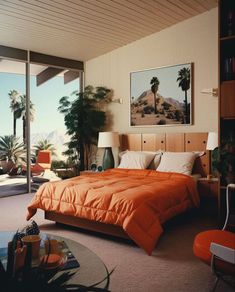 a bedroom with an orange comforter and palm trees in the window sill area