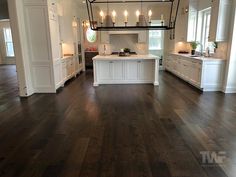 a large open kitchen with white cabinets and wood floors