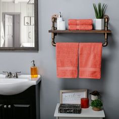 a bathroom with two orange towels hanging on the wall and a mirror over the sink