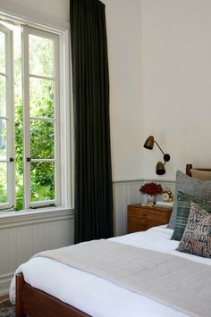 a bedroom with a large bed and two windows