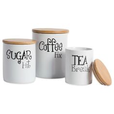 three white coffee canisters with wooden lids, one has a tea in it