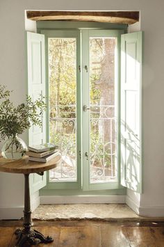 a table with a potted plant on top of it in front of a window