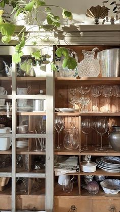 an open cabinet filled with lots of dishes and wineglasses on top of wooden shelves