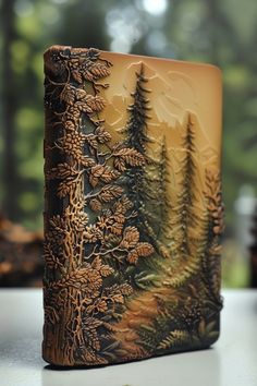 a book with trees on it sitting on a table in front of a forest scene