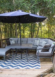 a patio with an umbrella and furniture on the deck in front of some trees,