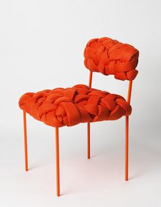 an orange chair sitting on top of a white floor next to a wooden pole with knoted ends