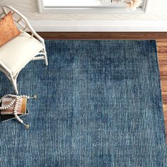 a blue rug with a chair and window in the background