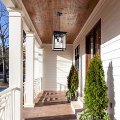 the front porch is lined with potted plants and hanging lanterns on either side of the house