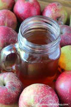 a jar of apple cider sitting next to some apples