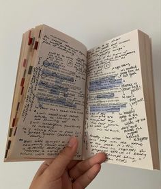 an open book with writing on it in someone's hand and the pages are lined up