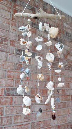 a wind chime made out of seashells hanging on a brick wall