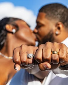 a bride and groom kissing in front of the sky with their wedding rings on their fingers