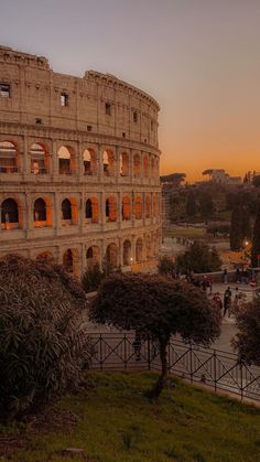 the roman colossion is lit up at night with people walking around in front