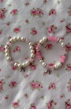 two bracelets with pearls and pink beads on a floral cloth covered tablecloth next to each other