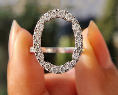 a diamond ring being held up by someone's hand with the middle section partially covered in diamonds