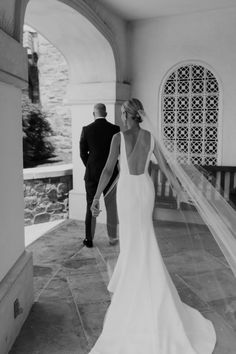 a bride and groom walking through an archway