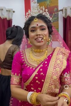 a woman in a pink sari with gold jewelry on her face and nose piercings