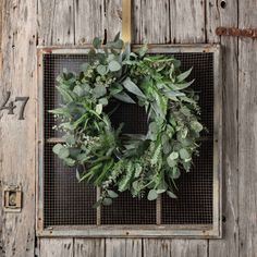 a green wreath hanging on the side of a wooden door with an iron grate