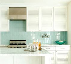 a kitchen with white cabinets and blue backsplash