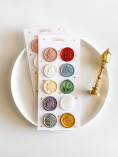 a white plate topped with lots of different types of buttons next to a golden key