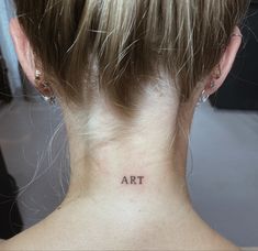 a woman's back neck with the word art tattooed on her left side ribcage