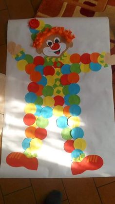 a child's paper cut out of a clown with colorful circles on the floor