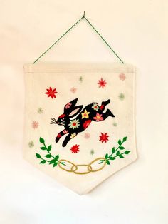 a white banner hanging on a wall with a black cat and red poinsettis