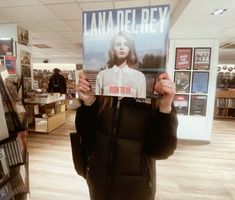 a woman holding up a sign in front of her face with the words lana del ray on it